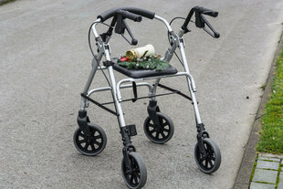 Ein Rollator mit Tannesnzweig und Trauerkerze auf einem Friedhof