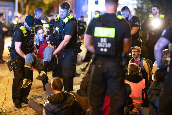 Aktivist:Innen der Neuen Generation sitzen auf dem Boden oder werden von Polizisten weggetragen