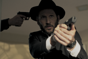 Filmszene: Ein Rabbi zielt mit einer Pistole